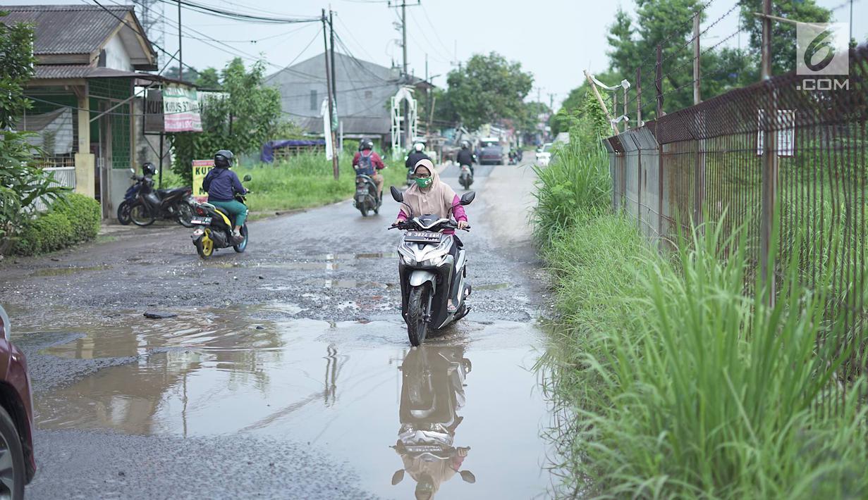 Pengendara sepeda motor melintasi jalan yang rusak di Jalan Raya Gas Alam, Depok, Jawa Barat, Selasa (7/5). Kondisi jalan yang tidak kunjung diperbaiki tersebut menjadi kubangan air setiap hujan serta berbahaya bagi keselamatan pengguna jalan. (Liputan6.com/Immanuel Antonius)