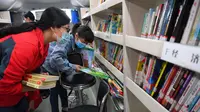 Orang-orang memilih buku di sebuah perpustakaan keliling di sebuah lingkungan permukiman di Changsha, Provinsi Hunan, China tengah (26/3/2020).  (Xinhua/Chen Zeguo)