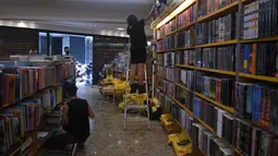 Relawan membersihkan toko buku setelah hujan lebat membanjiri di Petropolis, Brasil, 19 Februari 2022. Sebanyak 136 jenazah telah diidentifikasi hingga kini, menurut pejabat pertahanan sipil, di kota wisata yang biasanya indah, sekitar 60 km utara Rio de Janeiro. (MAURO PIMENTEL/AFP)