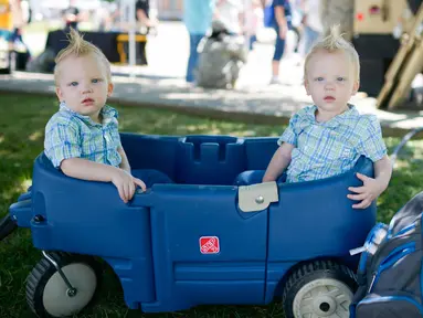 Pasangan kembar yang berusia 20 bulan dari Cleveland, Noah dan Owen Jury duduk dimobil mainan saat Festival Twins Days tahunan ke-42 di Twinsburg, Ohio (5/8). Festival ini mengumpulkan orang-orang yang memiliki kembaran. (AFP Photo/Dustin Franz)