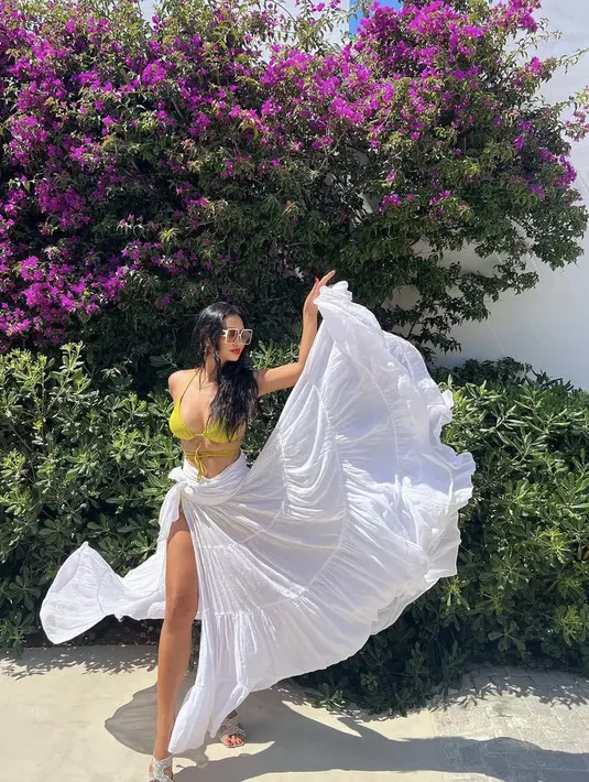 Ia juga tampil berbikini warna hijau dengan rok putih ruffle yang cukup lebar. Tak lupa ia mengenakan kacamatanya.  (@indahkalalo)