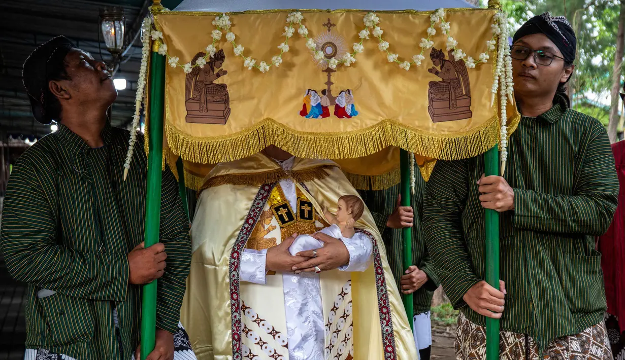 Gereja Hati Kudus Yesus ini dikenal memiliki ciri khas yakni memadukan unsur budaya lokal dalam setiap perayaan keagamaan. Tampak dalam foto, umat Katolik membawa patung bayi Yesus sambil menunggu Misa Malam Natal di Gereja Hati Kudus Yesus di Ganjuran, Bantul, Yogyakarta, pada Rabu 24 Desember 2025. (DEVI RAHMAN/AFP)
