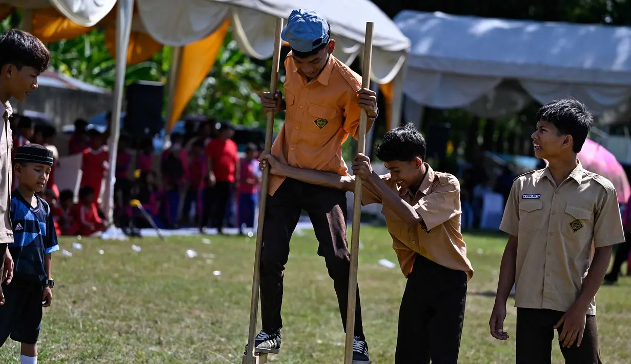 Siswa mengikuti permainan tradisional egrang pada Festival Permainan Tradisional Anak di Desa Wisata Lubok Sukon, Kecamatan Ingin Jaya, Aceh Besar, Aceh, Sabtu (25/7/2026). (AFP/ Chaideer Mahyuddin)