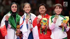 Karateka putri Indonesia, Cokorda Istri Agung Sanistyarani (kedua kanan) menunjukkan medali perunggu usai memenangkan pertandingan di babak final nomor Kumite 55 kg di Arena Karate JCC Senayan, Jakarta, Minggu (26/8). (Liputan6.com/Fery Pradolo)