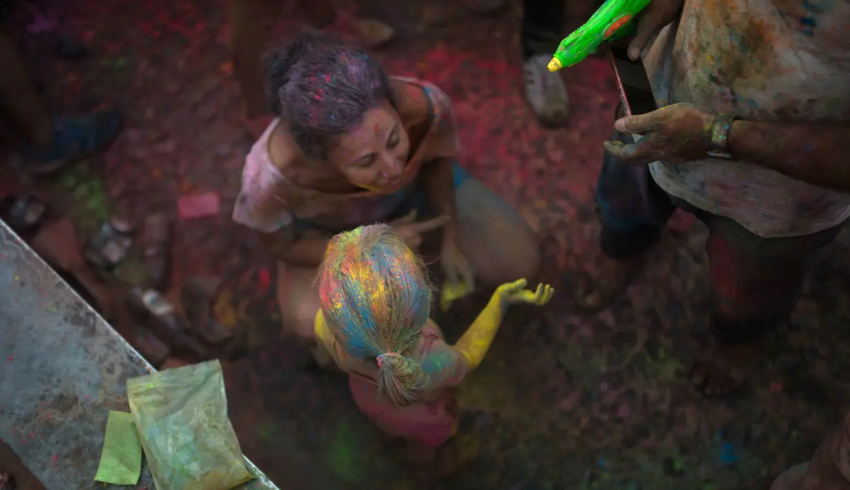 Seorang anak didampingi orang tua mengikuti Festival Monsoon Holi di Madrid, Spanyol (5/8). Peserta merayakan holi dengan saling melemparkan bubuk berwarna-warni atau saling menyiramkan air berwarna-warni. (AP Photo/Francisco Seco)