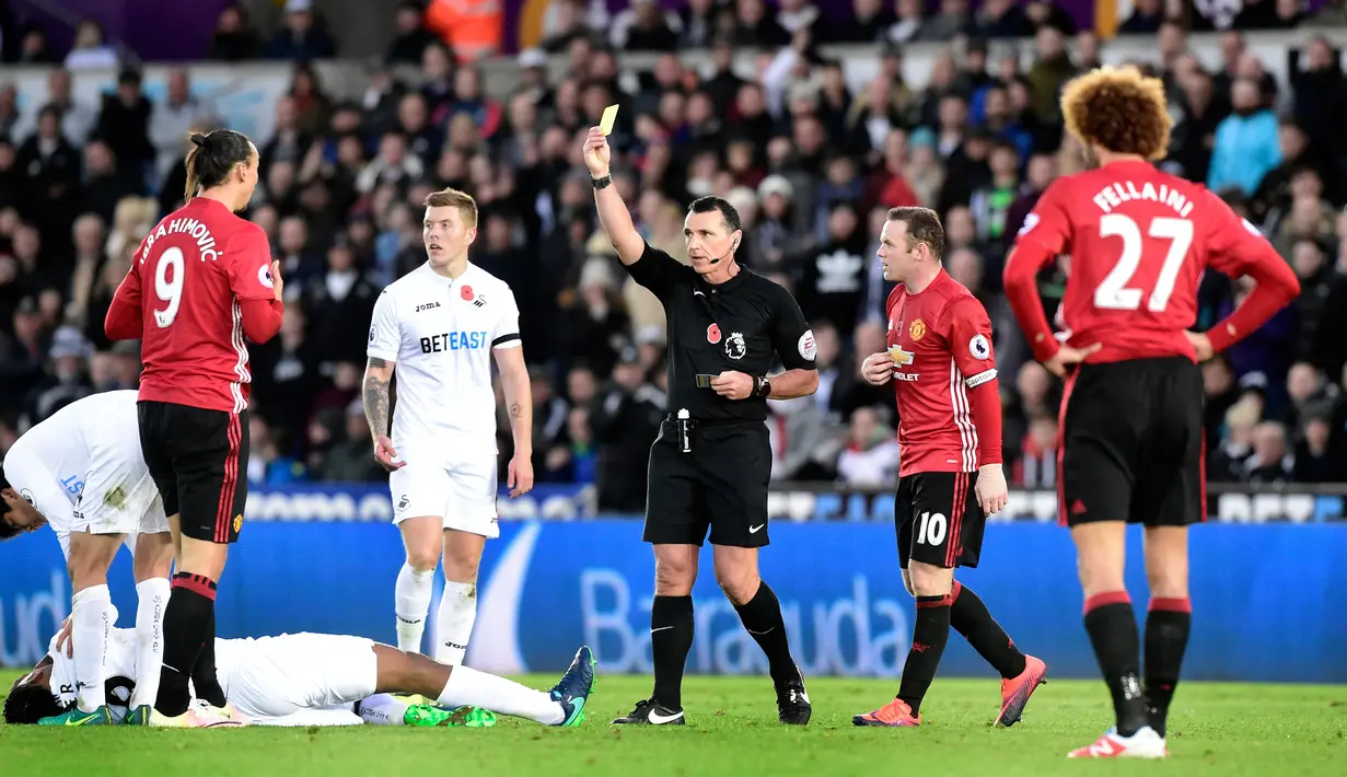 Wasit memberikan kartu kuning kepada Zlatan Ibrahimovic setelah melakukan pelanggaran kepada Leroy Fer saat pertandingan Liga Premier Inggris, Swansea City menjamu Manchester United di Stadion Liberty, Inggris (6/11). (Reuters/Rebecca Naden)