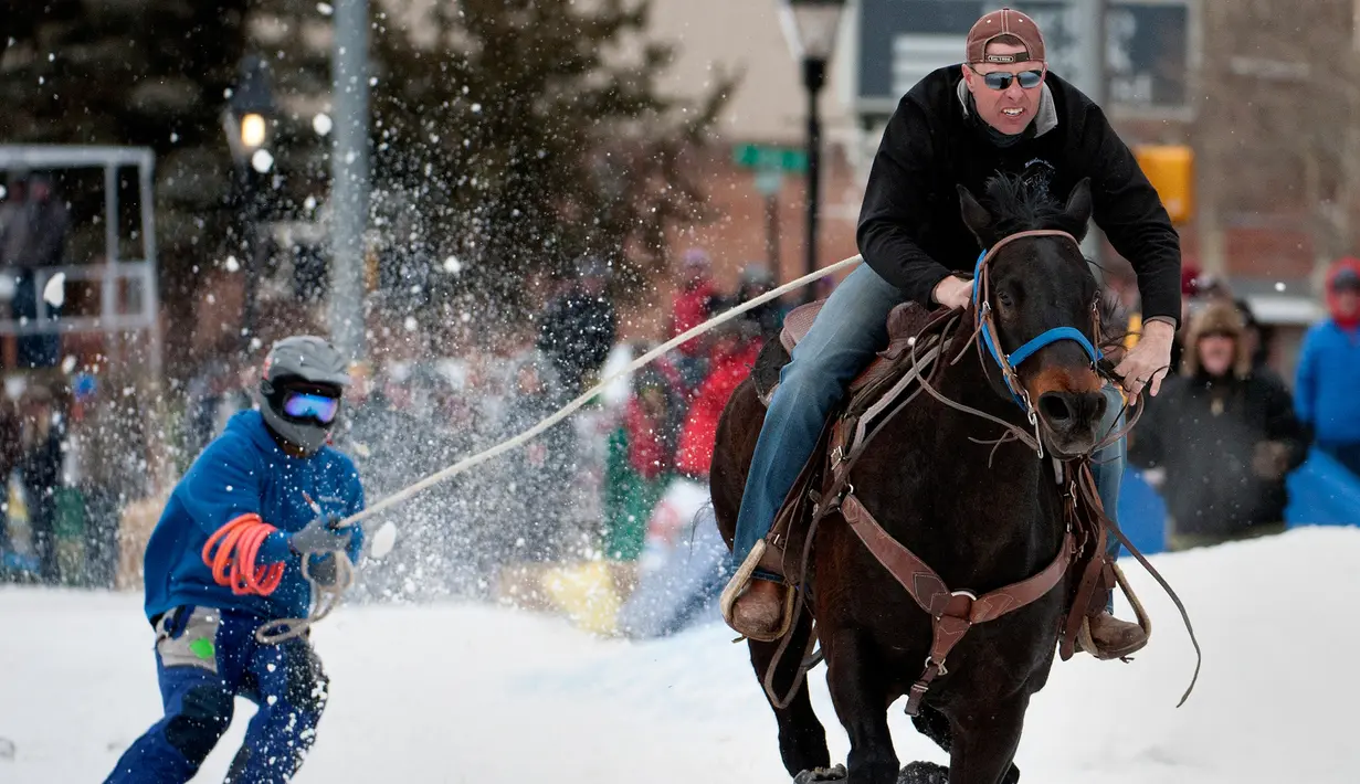 Joki yang bernama Eric Mikkelsen menarik pemain ski salju Shawn Gerber saat kompetisi Leadville Ski Joring ke-70 di Leadville, Colorado (4/3). Kompetisi ski joring dimulai sejak 1949 dan digelar setiap tahunnnya. (AFP Photo/Jason Connolly)