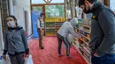 Orang-orang mengambil kebutuhan mereka di rak-rak sepatu di masjid Dedeman di distrik Sariyer, Istanbul pada 21 April 2020. Jelang Ramadan, masjid itu membuka supermarket gratis yang menyediakan kebutuhan sehari-hari secara gratis untuk warga membutuhkan yang terdampak Corona. (Bulent Kilic/AFP)