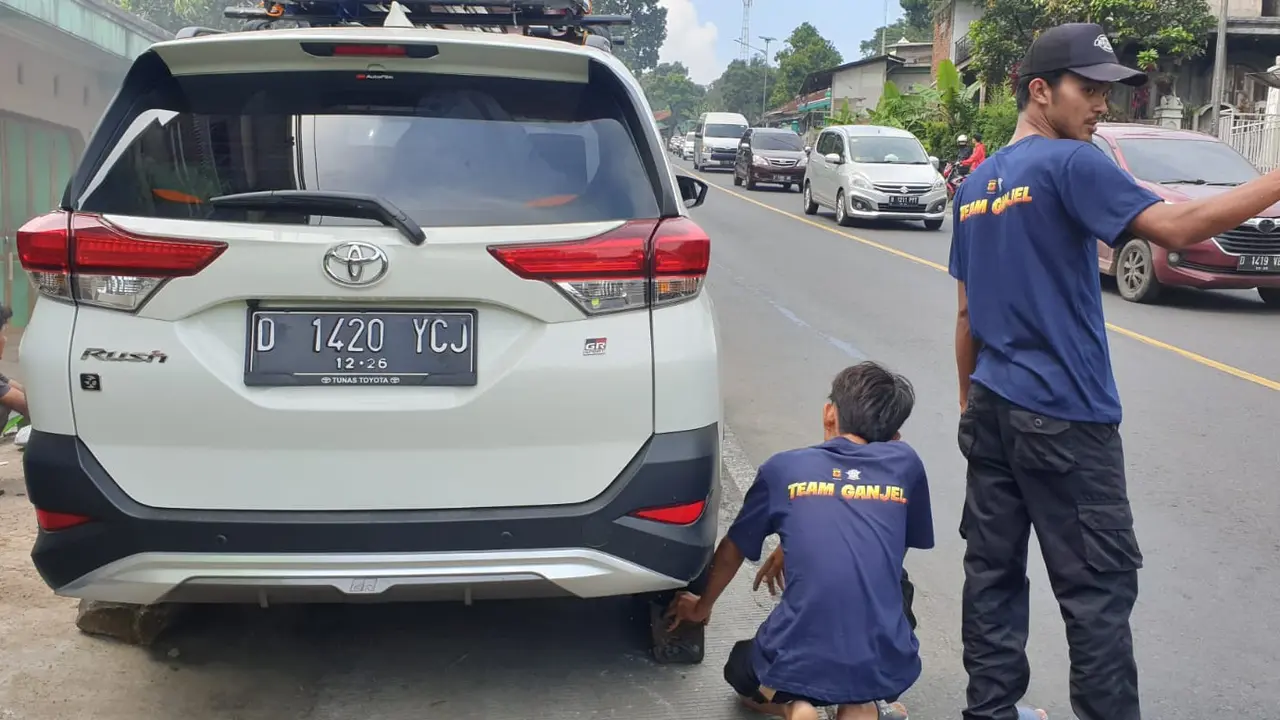 Dua orang anggota tim ganjel tanjakan polres Garut, Jawa Barat tengah memberikan bantuan kepada pemudik di Tanjakan Andir, Malangbong. (Liputan6.com/Jayadi Supriadin)