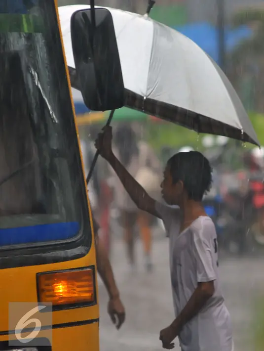 Seorang bocah pengojek payung saat menawarkan jasanya kepada penumpang bis yang turun di kawasan Tanah Abang, Jakarta, Selasa (9/2). Tidak ada tarif khusus yang ditawarkan oleh para pengojek payung tersebut. (Liputan6.com/Faisal R Syam)