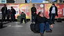 Para penumpang menunggu kereta mereka di luar pintu masuk stasiun kereta api Beijing di ibu kota China, Senin (21/1). Sebagian warga China yang tinggal di kota-kota besar mulai mudik untuk merayakan tahun baru Imlek bersama keluarga. (WANG ZHAO/AFP)
