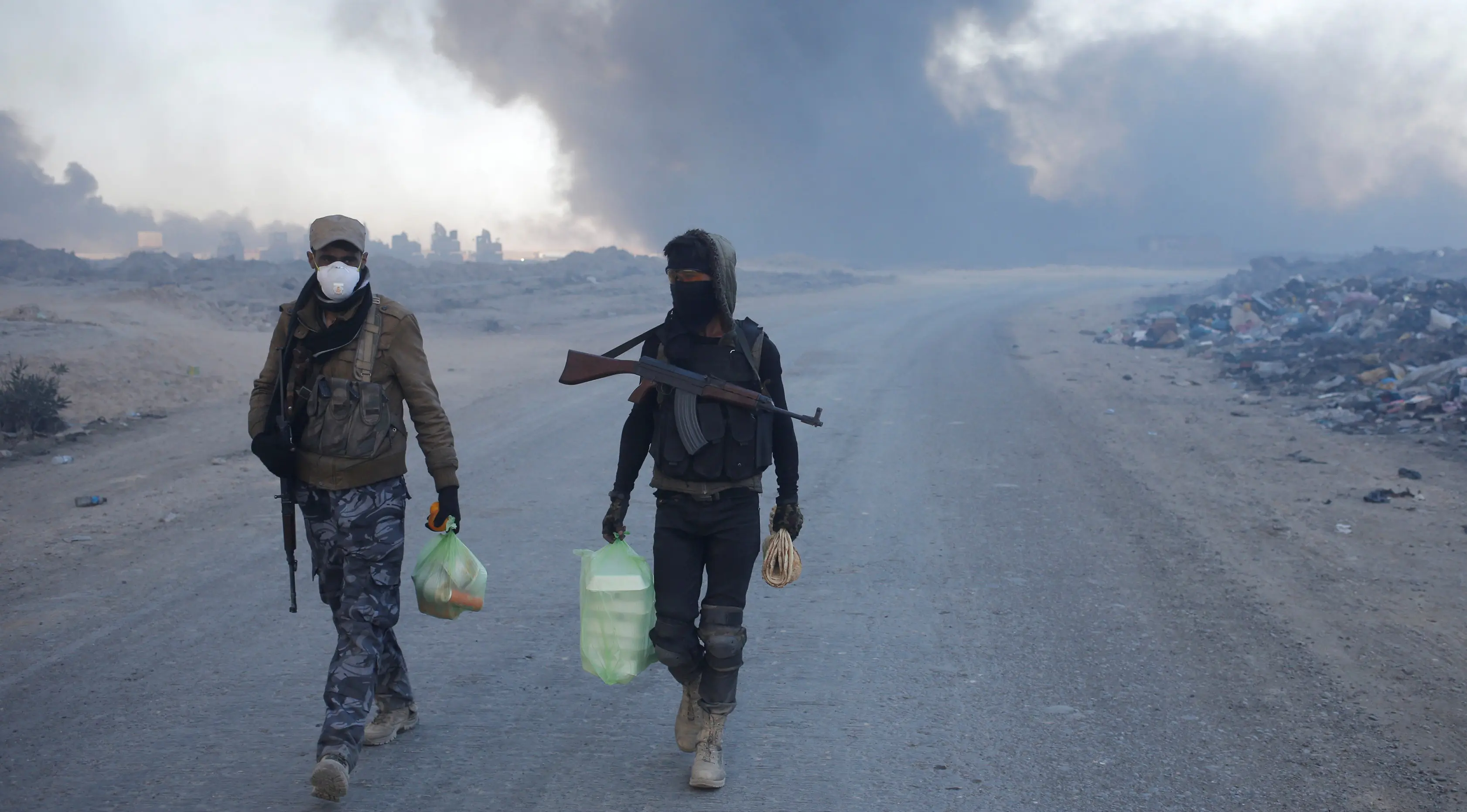 Petugas kepolisian berjalan di dekat kilang minyak yang dibakar oleh ISIS di Qayyara, selatan Mosul, Irak, (23/11). Sebelumnya, sekitar enam sumur minyak telah dibakar ISIS di kawasan tersebut. (REUTERS/Goran Tomasevic)