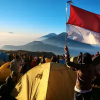 Pemandangan matahari terbit yang bertepatan dengan HUT Kemerdekaan RI di puncak Prau. Terlihat ribuuan pendaki memadati puncak gunung yang berada di kawasan Dieng, Jawa Tengah. Foto: Ahmad Ibo/ Liputan6.com.