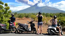 Sejumlah turis mengabadikan pemandangan erupsi Gunung Agung di Kabupaten Karangasem, Bali, Jumat (6/7). Mereka sibuk mengabadikan semburan abu vulkanik Gunung Agung.  (AFP FOTO / Sonny Tumbelaka)