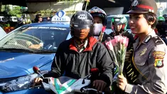 Sejumlah Polisi Wanita (Polwan) membagikan bunga kepada pengendara yang melintas di perempatan Slipi, Jakarta, Selasa (21/4/2015). Pembagian bunga ini dalam rangka memperingati hari Kartini.(Liputan6.com/Johan Tallo)
