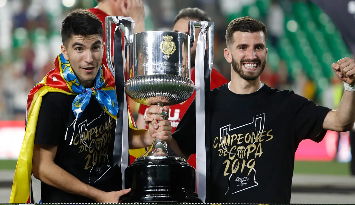 Dua pemain Valencia berpose dengan trofi Copa Del Rey usai pertandingan melawan Barcelona pada babak final di stadion Benito Villamarin di Seville, Spanyol (25/5/2019). Barcelona kalah 1-2 dari Valencia lewat gol Kevin Gameiro dan Rodrigo. (AP Photo/Miguel Morenatti)