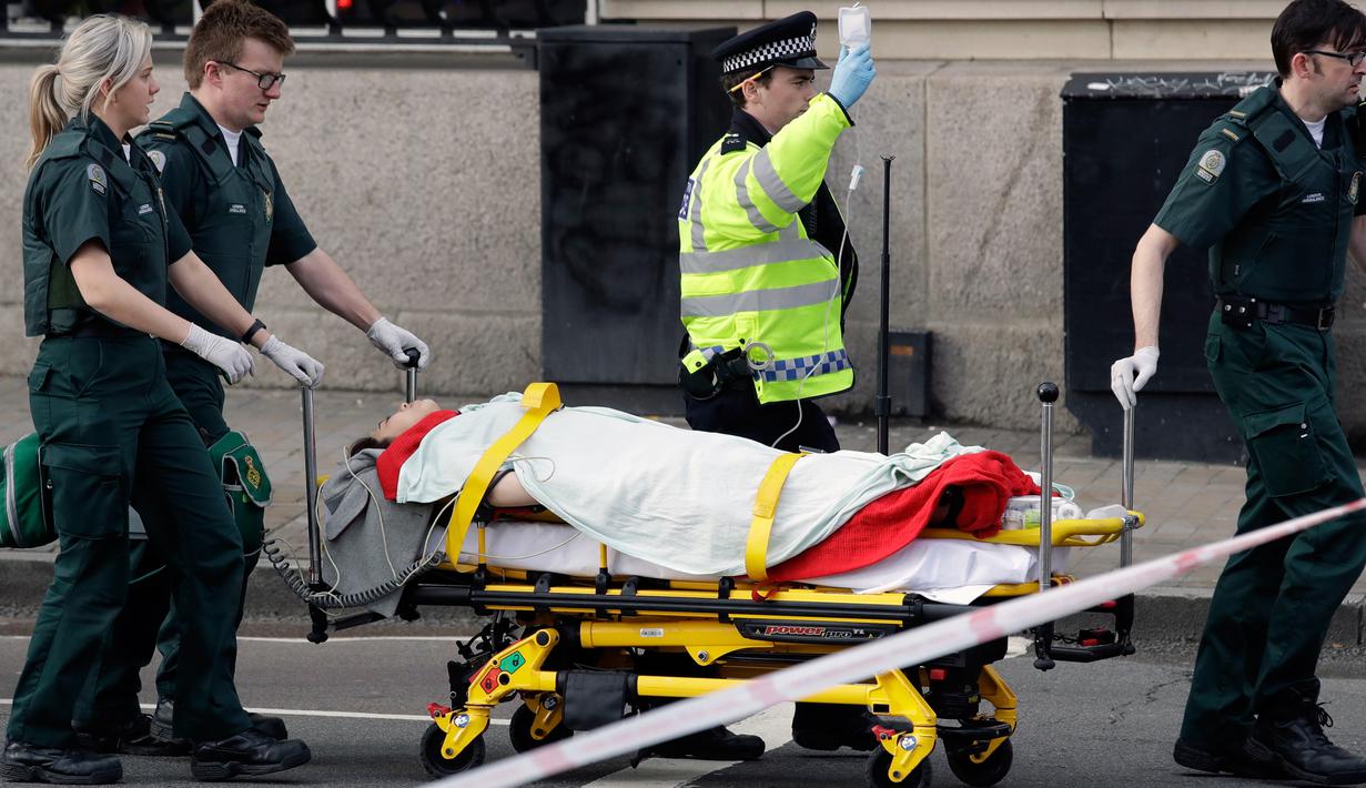 Petugas mengevakuasi korban terluka dalam serangan teror di dekat gedung Parlemen Inggris, London, Rabu (22/3). Pelaku penyerangan menembaki sejumlah pejalan kaki sambil mengemudikan mobilnya di jembatan Westminster. (AP Photo/Matt Dunham)