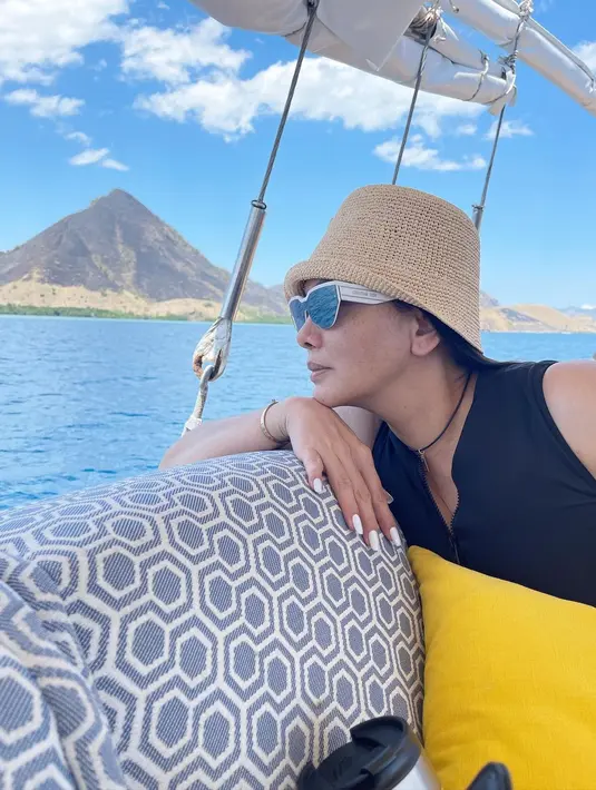 Labuan Bajo kini jadi primadona baru para pelancong. Salah satu foto yang diunggah Fitri Salhuteru enggak kaleng-kaleng. Menampilkan Fitri Salhuteru bersandar di sofa empuk motif abstrak. Ia tampil gaya dengan atasan hitam, topi bundar, plus kacamata seraya memegang bantal kuning berukuran mini. Yang bikin spesial, latar panorama laut dan perbukitan. Secantik itu. (Foto: Instagram @fitri_salhuteru)