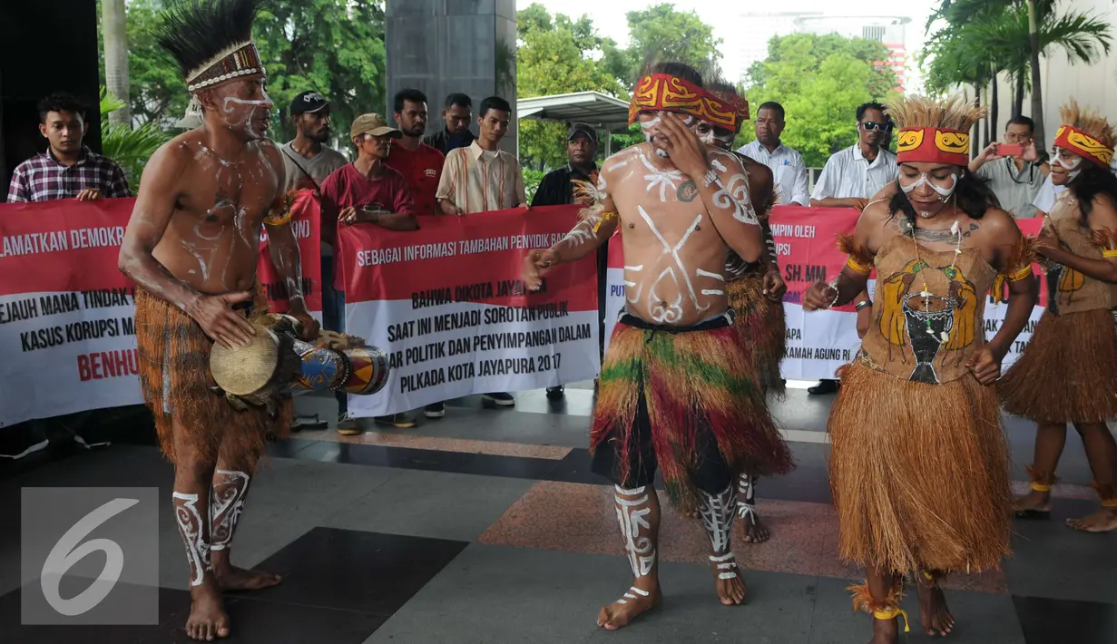 Sejumlah pemuda Papua mengenakan pakaian adat menari saat menggelar unjuk rasa di depan Gedung KPK, Jakarta, Senin (19/12). Mereka melakukan aksi teaterikal dan meminta KPK mengusut sejumlah kasus dugaan korupsi. (Liputan6.com/Helmi Affandi)