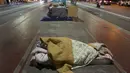 Seorang tunawisma tidur di atas trotoar saat malam dengan cuaca dingin di pusat kota Sao Paulo, 19 Juli 2017. Menurut pejabat setempat, setidaknya 16.000 tunawisma tinggal di kota Sao Paulo. (AP Photo / Andre Penner)