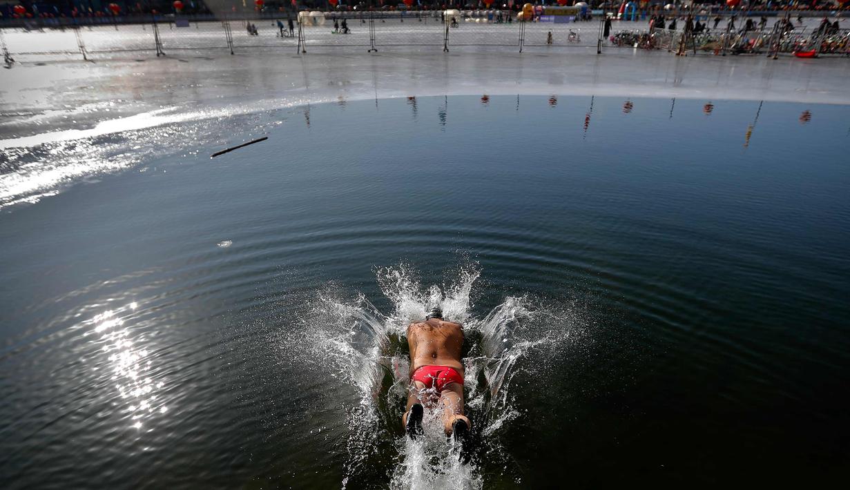 Seorang pria menyelam ke air setengah beku di Danau Shichahai di Beijing, China (24/1). Menurut beberapa penduduk setempat, berenang di air dingin baik untuk kesehatan. (AP Photo / Andy Wong)