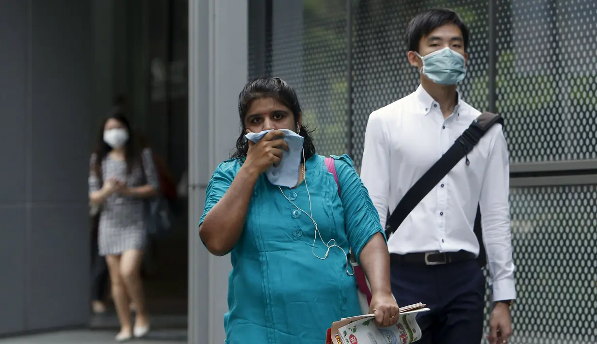 Pekerja memakai masker saat berjalan di pusat bisnis, Singapura (25/9/2015). Menurut Badan Lingkungan Nasional Singapura kabut Polutan Standar Indeks (PSI) mencapai tinggi 341 pada hari Jumat. (REUTERS/Edgar Su)