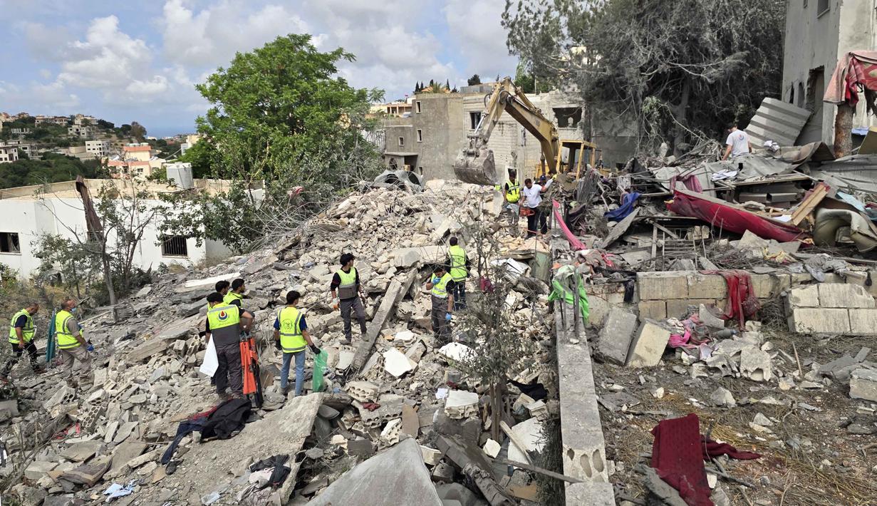 Para pekerja pertahanan sipil Lebanon menyisir reruntuhan, sehari setelah serangan Israel di desa Deir Qanun al-Nahr, Lebanon Selatan, pada Rabu 20 Mei 2026. (KAWNAT HAJU/AFP)