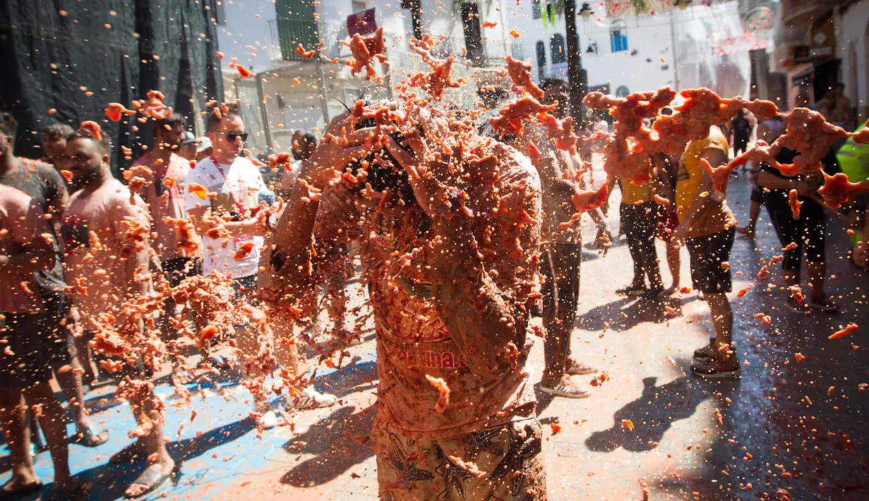 Seorang peserta bersuka ria dengan tomat yang hancur saat berpartisipasi dalam festival tahunan "Tomatina" di Bunol, salah satu kota di timur Spanyol, Rabu (29/8/2019). Perang tomat yang penuh kehebohan itu rutin diadakan setiap Rabu terakhir bulan Agustus. (JAIME REINA / AFP)