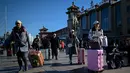 Penumpang berjalan dengan membawa tas menuju pintu masuk stasiun kereta api Beijing di ibu kota China, Senin (21/1). Sebagian warga China yang tinggal di kota-kota besar mulai mudik untuk merayakan tahun baru Imlek bersama keluarga. (WANG ZHAO/AFP)