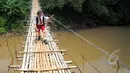 Seorang siswa SD melintas di atas jembatan gantung di atas kali Ciliwung untuk menuju ke sekolah, Jakarta, Selasa (17/3/2015). Jembatan tersebut menghubungkan Kelapa Dua Depok dengan Lenteng Agung (Liputan6.com/Yoppy Renato)