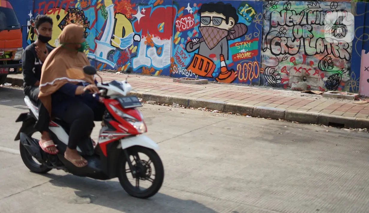 Pengendara sepeda motor melintas di depan mural bertema pandemi virus corona COVID-19 di kawasan Sunter, Jakarta, Selasa (2/6/2020). Mural tersebut dibuat sebagai wujud dukungan terhadap tenaga medis serta masyarakat agar tetap semangat menghadapi pandemi COVID-19. (Liputan6.com/Immanuel Antonius)