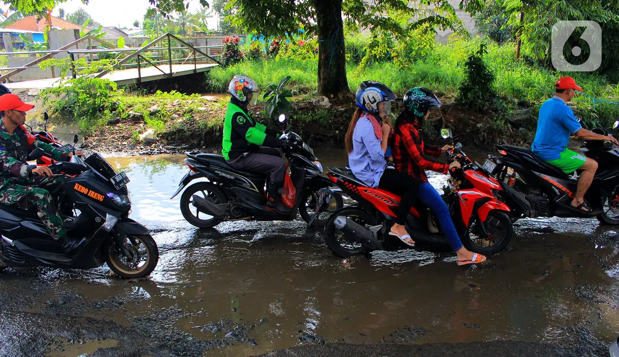 Pengendara motor menerobos lubang yang ada di Jalan Raya Bojonggede, Bogor, Jawa Barat, Sabtu (22/2/2020). Jalan Raya Bojonggede yang berlubang hingga kini belum juga diperbaiki pemerintah setempat membuat kondisi lalu lintas tersendat (merdeka.com/Magang/Muhammad Fayyadh)