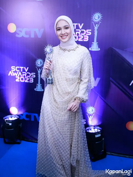 Penampilan Cut Syifa di carpet biru dengan memegang piala penghargaan yang baru saja diraih.  Cut Syifa meraih dua piala kategori Aktris Utama Paling Ngetop dan Artis Paling Sosmed. Ia tampil cantik dengan gaun cantik berwarna nude dengan aksen gold di setiap permukaannya.  [Foto: Bayu Herdianto/KapanLagi.com]