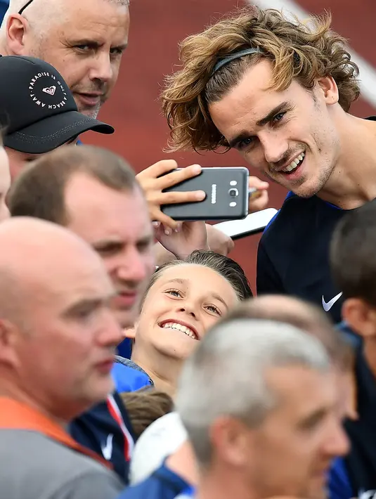 Penyerang Atletico Madrid, Antoine Griezmann foto bersama dengan para fans saat sesi latihan untuk persiapan kualifikasi Piala Dunia 2018 melawan Swedia di Clairefontaine-en-Yvelines (5/6). (AFP Photo/Franck Fife)