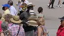 Seorang pria mencoba menjual topi untuk melindungi dari matahari kepada turis di pusat kota Madrid, Spanyol, Minggu (12/6/2022). Layanan cuaca Spanyol mengatakan massa udara panas dari Afrika utara memicu gelombang panas besar pertama di negara itu tahun ini dengan suhu diperkirakan naik hingga 43 derajat Celcius (109 derajat Fahrenheit) di area tertentu.  (AP Photo/Paul White)