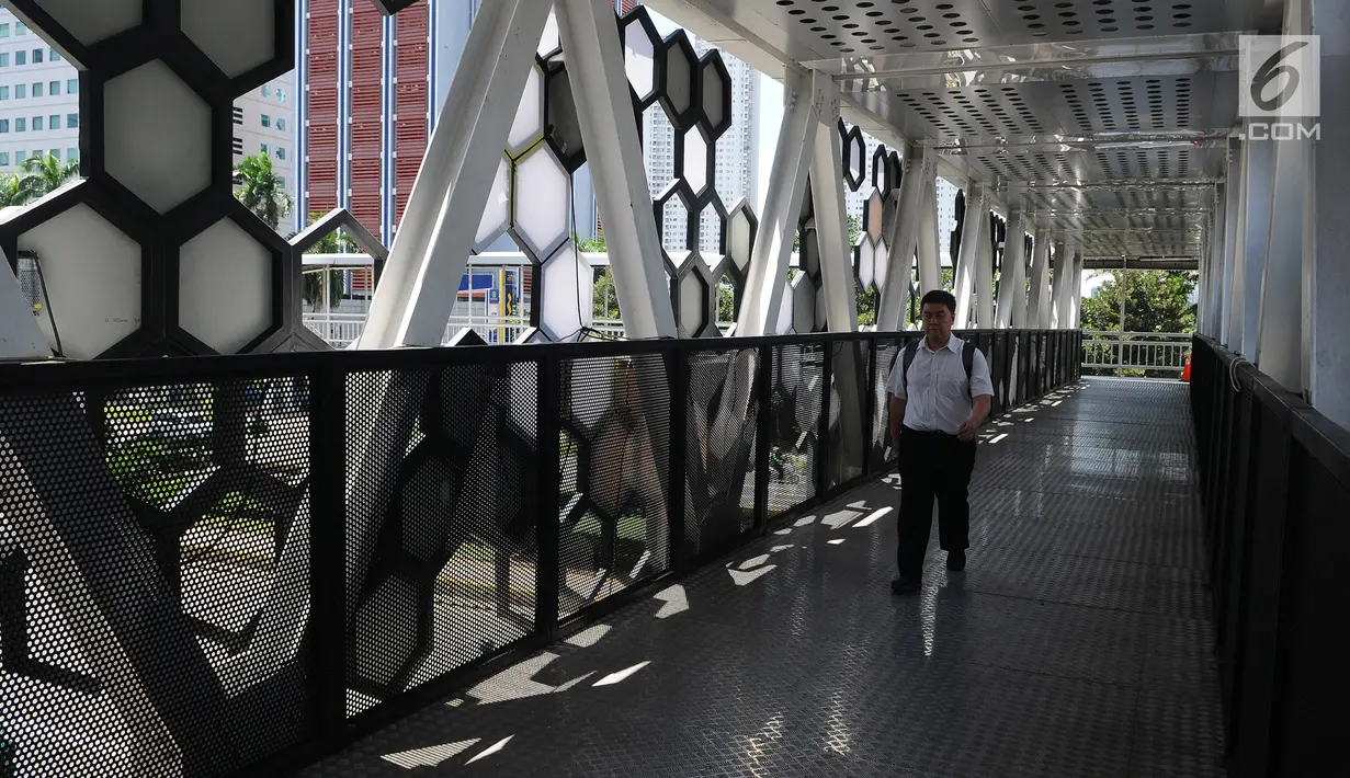 Pejalan kaki melintasi jembatan penyeberangan orang (JPO) Dukuh Atas di Jalan Jenderal Sudirman, Jakarta, Jumat (4/1). Revitalisasi JPO Dukuh Atas sudah rampung. (Liputan6.com/Herman Zakharia)