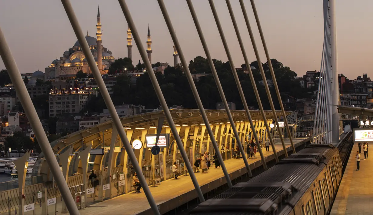 Penumpang menunggu kereta di Jembatan Tanduk Emas dengan latar belakang Masjid Suleymaniye di Istanbul (26/7/2019). Dengan Laut Marmara, Tanduk Emas membentuk semenanjung dengan pelabuhan alam yang dalam. (AP Photo/Emrah Gurel)