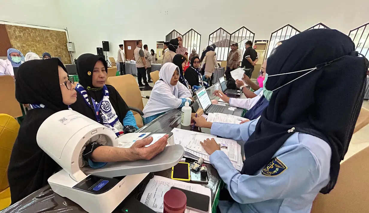 Petugas memeriksa kesehatan calon haji setibanya di Asrama Haji Pondok Gede, Jakarta, Selasa (21/4/2026). Sebanyak 393 jemaah haji kelompok terbang (kloter) pertama embarkasi Jakarta-Pondok Gede (JKG 01) secara resmi mulai memasuki Asrama Haji Pondok Gede, Jakarta Timur. (merdeka.com/Arie Basuki)