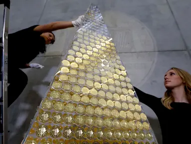 Karyawan rumah emas ProAurum menyusun koin emas yang disebut sebagai pohon Natal di Munich, Jerman, 3 Desember 2018. Pohon Natal ini terbuat dari 2.018 koin emas filharmonik wina senilai 2.3 euro atau sekitar 370 milliar rupiah. (AP/Matthias Schrader)
