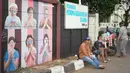 Warga duduk di dekat mural bergambar simbol orang berdoa menggunakan masker di kawasan Juanda, Kota Depok, Jumat (26/6/2020). Mural yang dibuat warga itu bertujuan memberi edukasi untuk menggunakan masker sebagai salah satu pencegahan dan penyebaran COVID-19. (Liputan6.com/Immanuel Antonius)