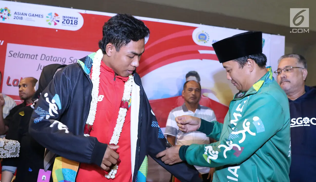 Menpora, Imam Nahrawi (kanan) memakaikan jaket Asian Games kepada juara dunia lari 100m putra U-20, Lalu Muhammad Zohri saat penyambutan di Terminal 3 Bandara Soetta, Tangerang, Selasa (17/7). (Liputan6.com/Helmi Fithriansyah)