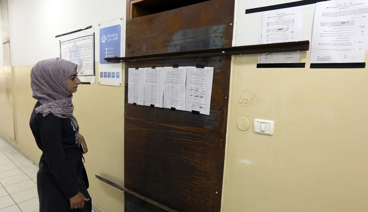 Karyawan Palmedia melihat pengumuman militer Isarel yang terpasang di pintu kantor mereka di Kota Hebron, Tepi Barat, Rabu (18/10). Pengumuman yang ditempelkan menyebutkan perusahaan tersebut ditutup selama enam bulan ke depan. (HAZEM BADER/AFP)