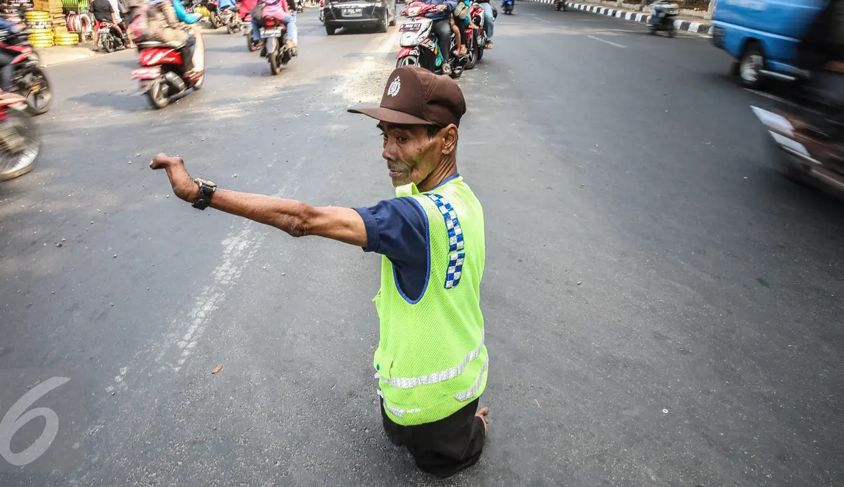 Pak Mamat (73 tahun) tengah mengatur arus lalu lintas di Jalan Raya Ciracas, Jakarta, Minggu (20/9/2015). Cacat fisik sejak lahir tidak membuat pria asli warga Ciracas ini putus harapan dalam menghidupi keluarganya. (Liputan6.com/Faizal Fanani)