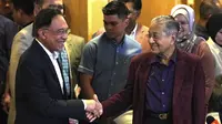 Perdana Menteri Malaysia Mahathir Mohamad (kanan) berjabat tangan dengan Anwar Ibrahim di Putrajaya, Malaysia, Sabtu (22/2/2020). Sebelumnya, Mahathir telah berjanji akan menyerahkan jabatannya kepada Anwar Ibrahim. (AP Photo/Vincent Thian)