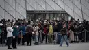 Pengunjung mengantre di depan Pyramid, pintu masuk utama menuju museum Louvre, di Paris, Rabu (4/3/2020). Louvre di Paris, museum yang paling banyak dikunjungi di dunia, kembali dibuka setelah pegawai yang khawatir dengan penularan virus corona setuju kembali masuk kerja. (Philippe LOPEZ/AFP)