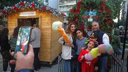Orang-orang berfoto di kampung Natal di daerah Ashrafieh, Beirut, Lebanon, 6 Desember 2020. Sebuah kampung Natal dibuka pada Minggu (6/12) bagi para pedagang yang tokonya hancur akibat ledakan pelabuhan pada 4 Agustus lalu. (Xinhua/Bilal Jawich)