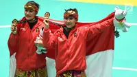 Pasangan pesilat Indonesia, Ayu Sidan Wilantari dan Ni Made Dwiyanti membentangkan bendera merah putih saat merayakan kemenangan usai meraih medali emas nomor seni ganda putri di Padepokan Pencak Silat (TMII, Rabu (29/8). (Merdeka.com/ Imam Buhori)
