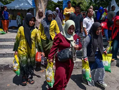Warga membawa beras usai mengantre membeli kebutuhan pokok di salah satu pasar di Surabaya, Jawa Timur pada Selasa 23 September 2025. (Juni KRISWANTO/AFP)