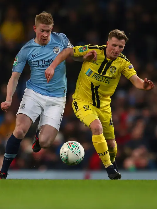 Gelandang Manchester City, Kevin De Bruyne berebut bola dengan pemain Burton Albion, Jamie Allen pada laga leg pertama semifinal Piala Liga Inggris di Stadion Etihad, Kamis (10/1). Manchester City menang telak atas Burton Albion 9-0. (AP/Dave Thompson)