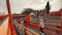 Warga beraktivitas di sekitar Jembatan Penyeberangan Orang (JPO) di Jalan Tegar Beriman, Cibinong, Kabupaten Bogor, Jawa Barat, Minggu (14/6/2026). (Kapanlagi.com/Budy Santoso)